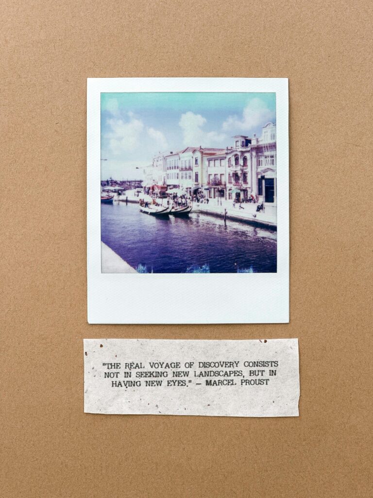 Polaroid photo of Aveiro canal with Marcel Proust quote on brown background, evokes discovery.