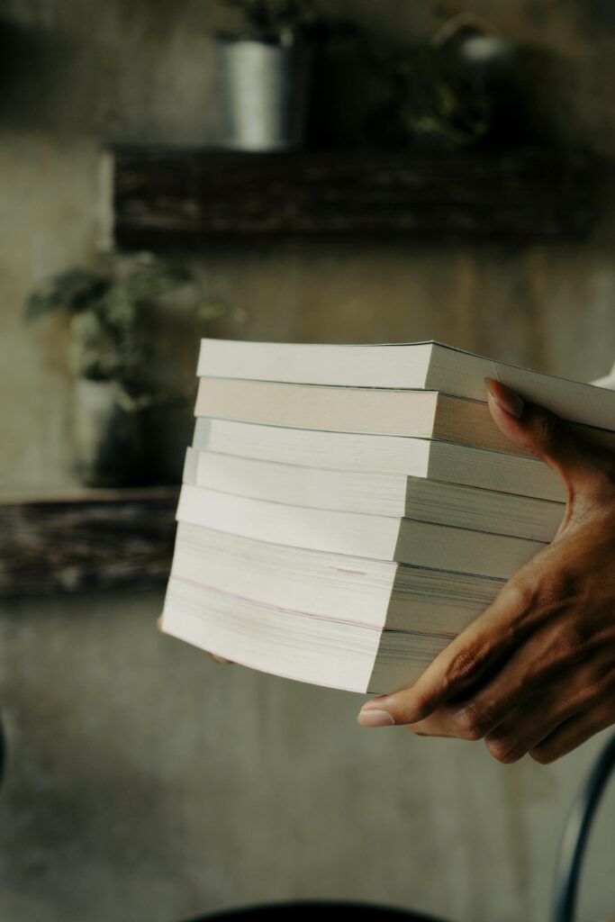 Close-up of hands holding a stack of books indoors, creating a cozy and educational atmosphere.