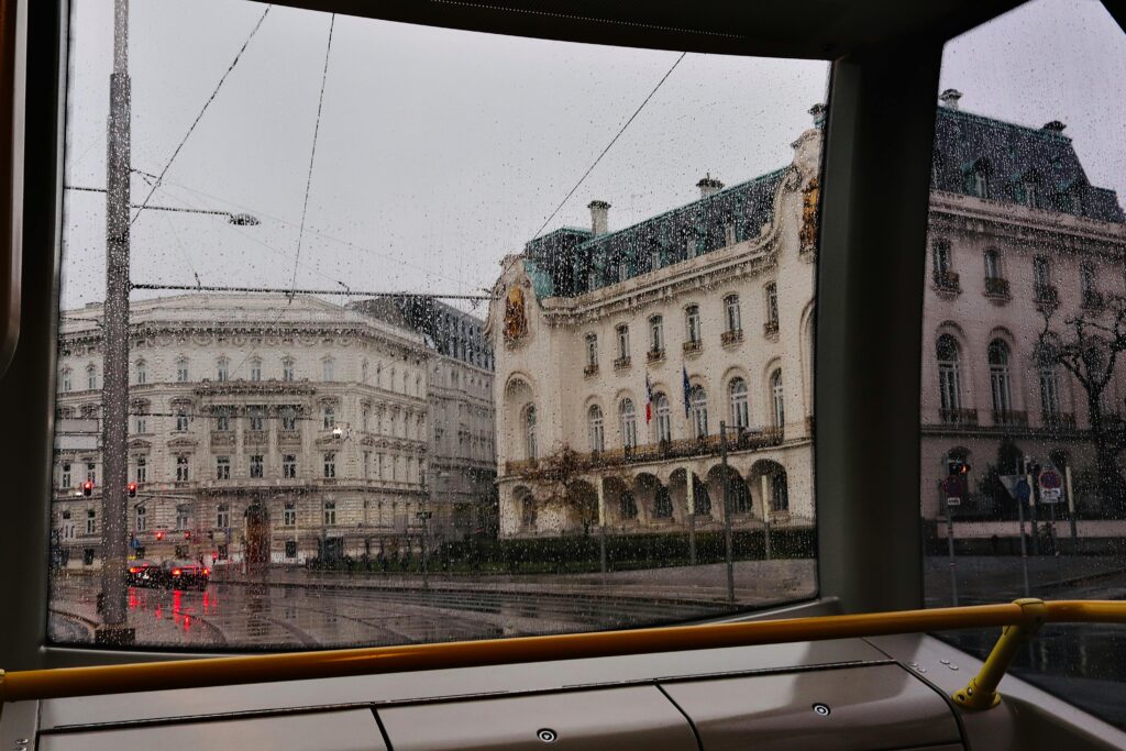 View of Vienna's historic buildings through rainy tram windows, capturing the city's urban charm.