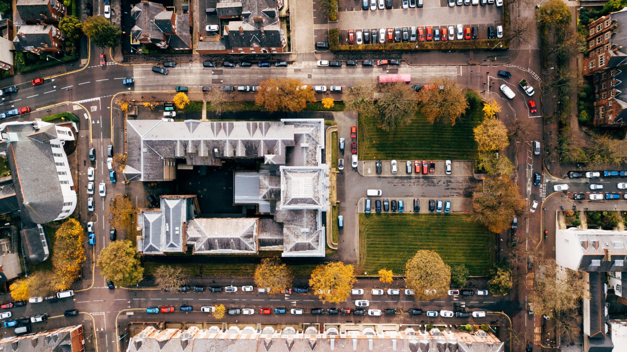 High-angle shot of urban streets and architecture in Belfast, showcasing parked cars and autumn trees.