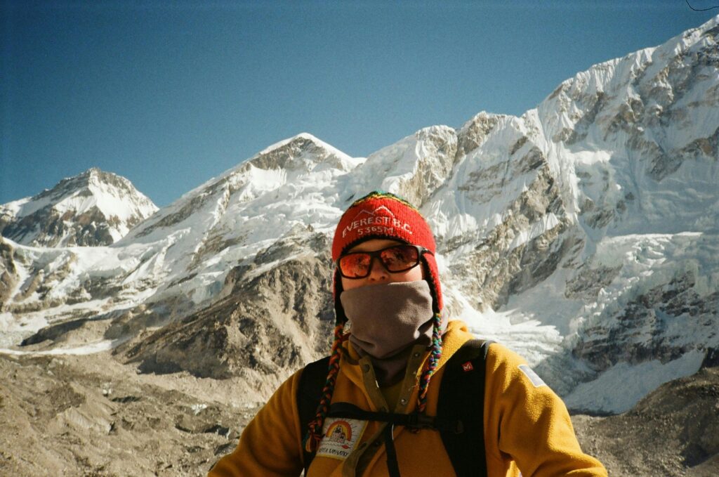 A mountaineer dressed for cold weather in Namche, Nepal, with the stunning Himalayan mountains as a backdrop.