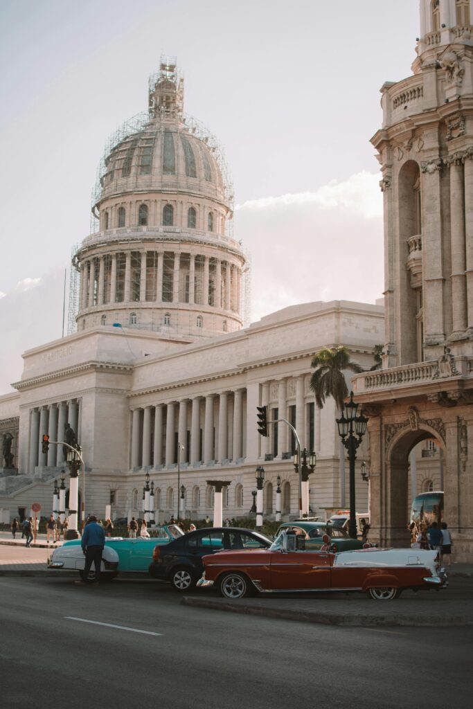 Classic cars by El Capitolio, Havana, showcasing Cuba's vintage charm and architectural beauty.