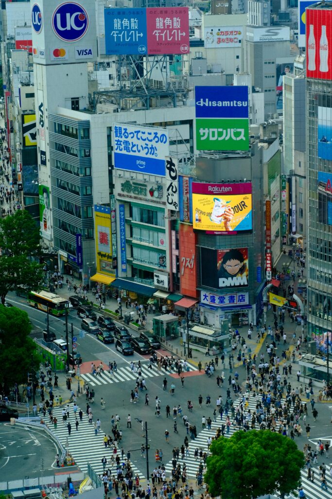 A bustling aerial view of Shibuya Crossing, Tokyo, showcasing vibrant urban life and colorful advertisements.