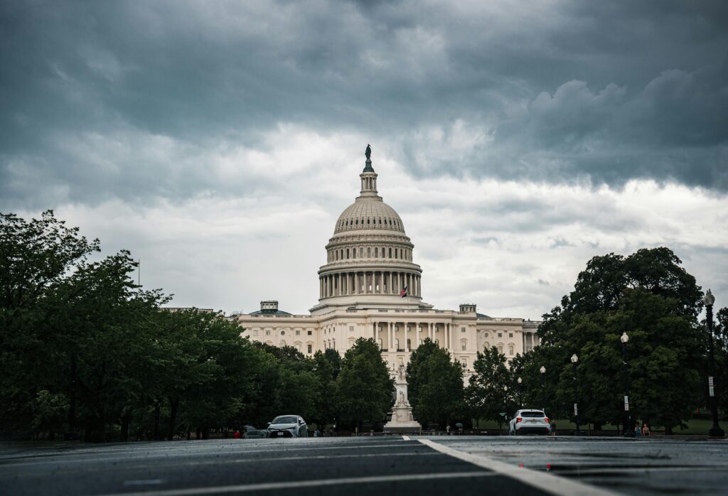 A dramatic view of the US Capitol under cloudy skies in Washington, DC.