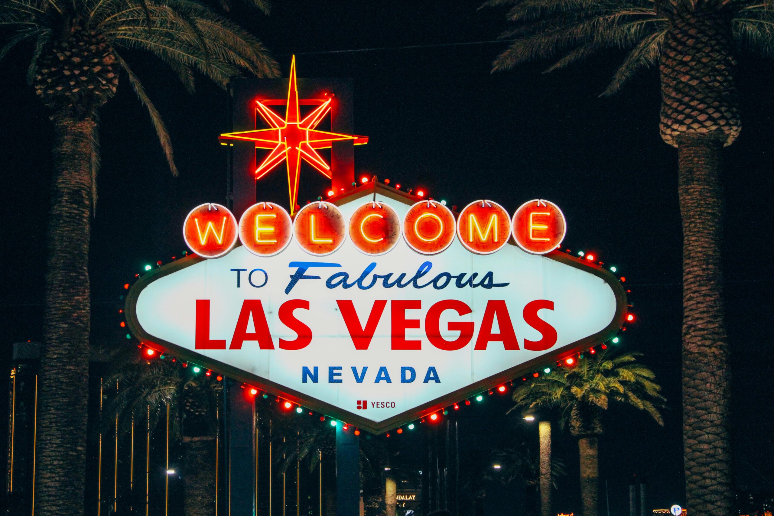 The iconic Welcome to Fabulous Las Vegas sign illuminated at night with palm trees in the background.