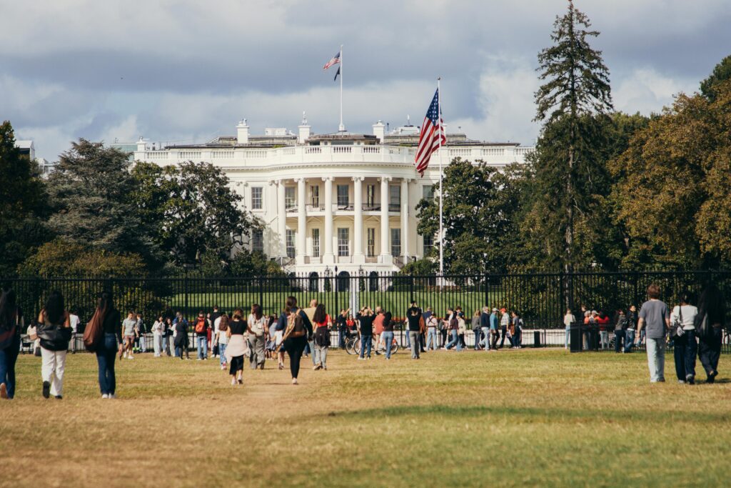 Tourists gather outside the White House on a sunny day, capturing the landmark's grandeur.