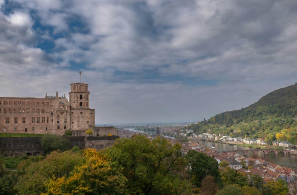 Scenic view of Heidelberg Castle with autumn foliage and cityscape along the Neckar River.