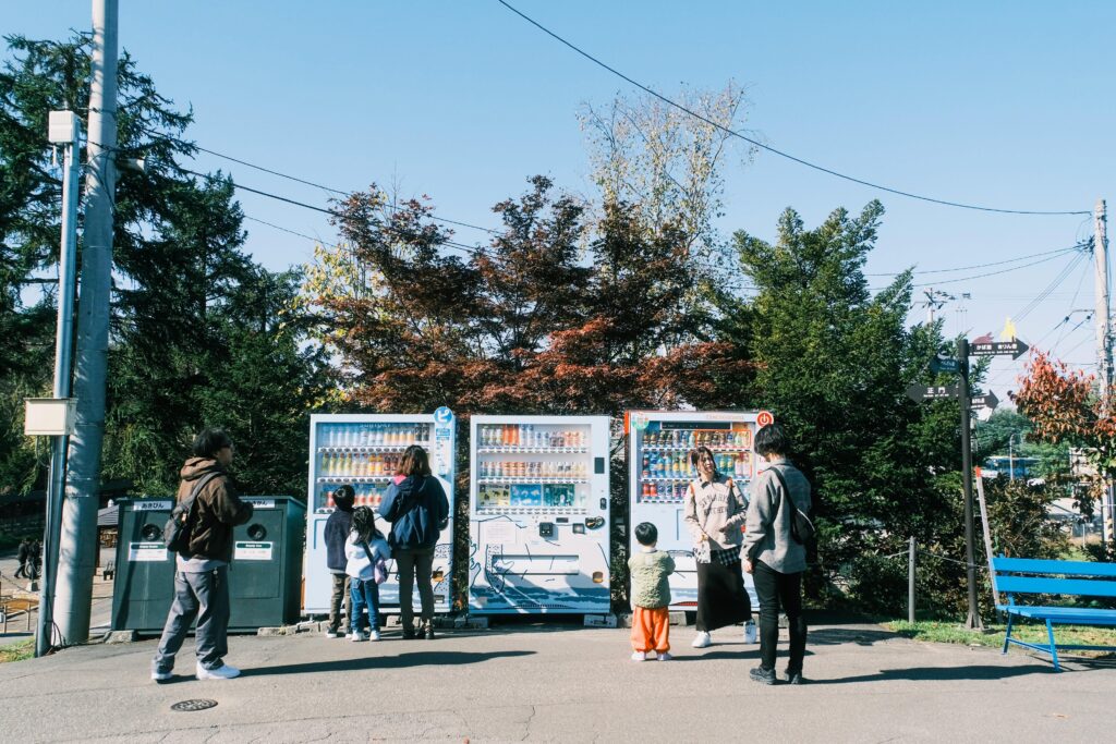 People interacting with vending machines in a park on a clear day.