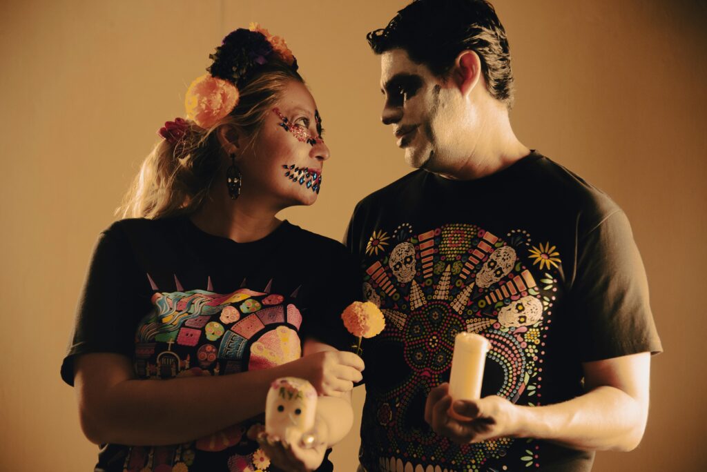Couple celebrating Day of the Dead with colorful face paint and traditional attire.
