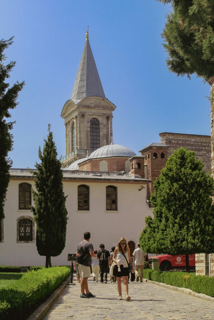 People strolling in the courtyard of Topkapi Palace on a sunny day in Istanbul.
