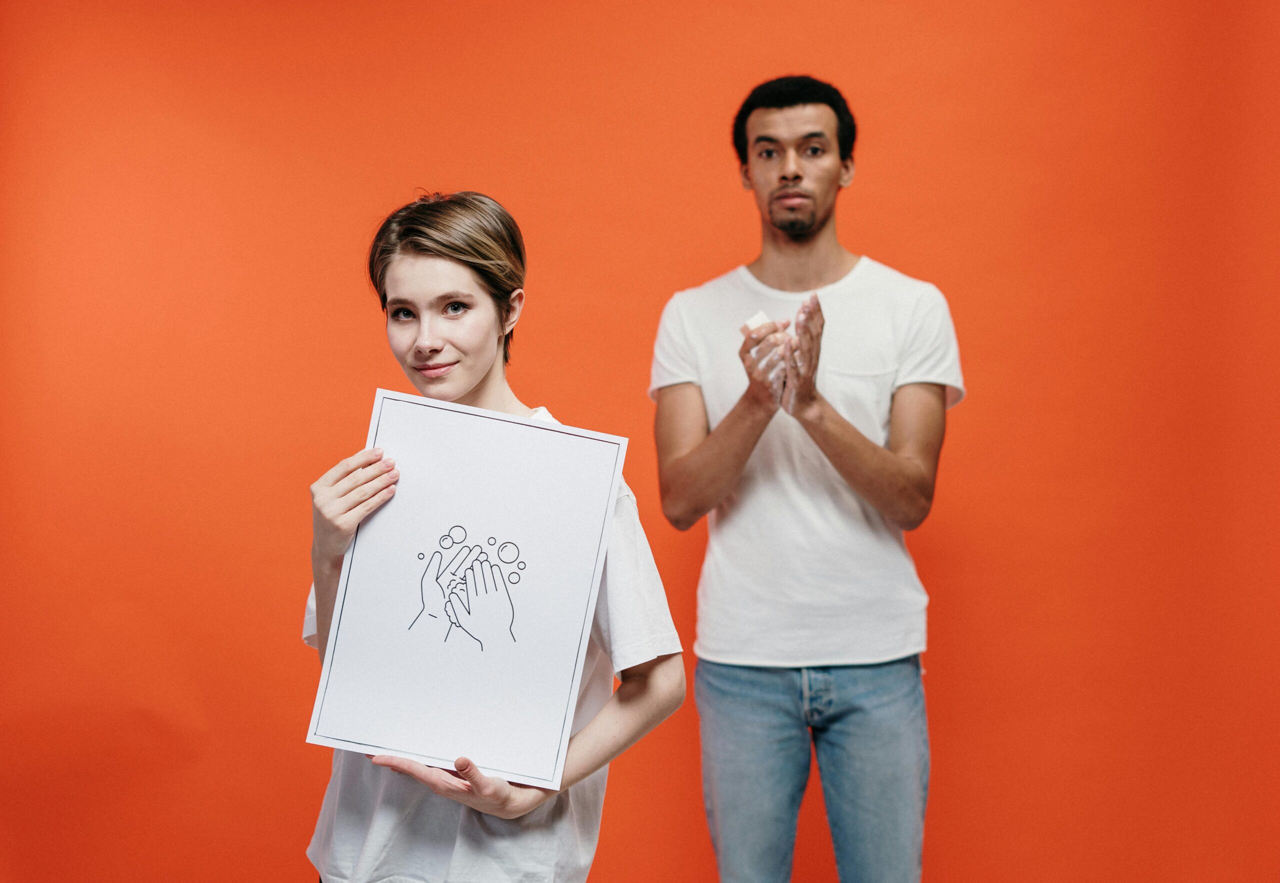 Illustrative photo of young adults promoting hand washing for hygiene on an orange background.