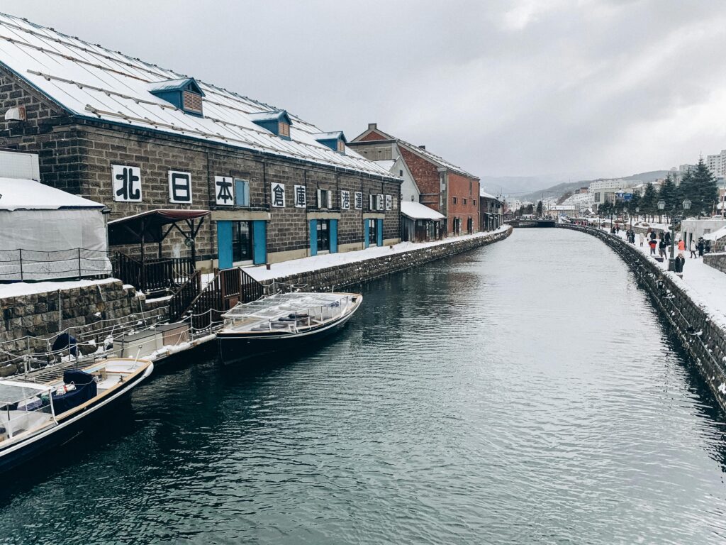 Beautiful winter scene of a historic canal with snow-covered buildings and boats, exuding a serene atmosphere.