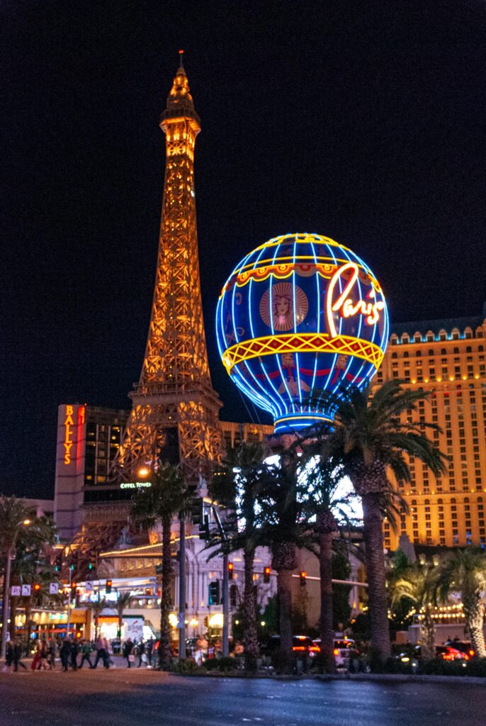 Night view of the Paris Hotel and Casino in Las Vegas with the illuminated Eiffel Tower and neon lights.