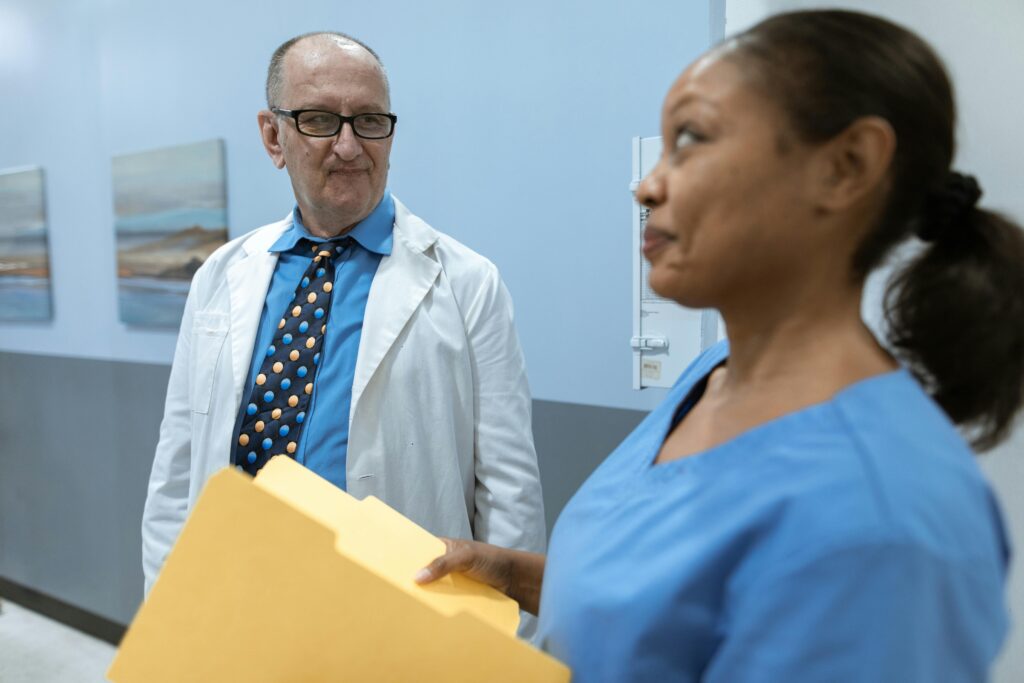 A doctor and nurse in conversation about patient records in a hospital corridor.