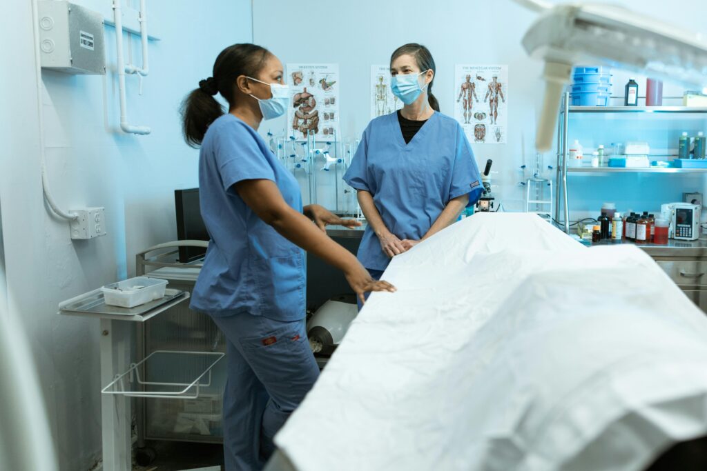 Medical professionals in scrubs and masks discussing in a clinical environment.