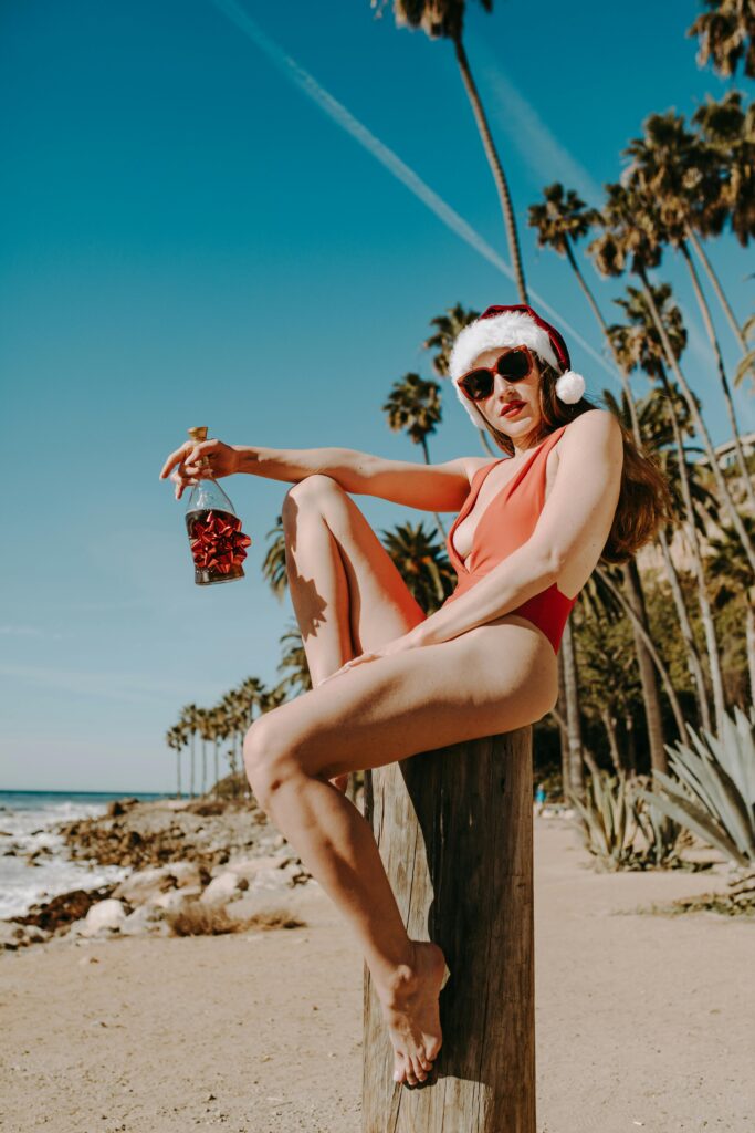 Woman in a Santa hat enjoying a sunny beach day, mixing holiday spirit with summer relaxation.