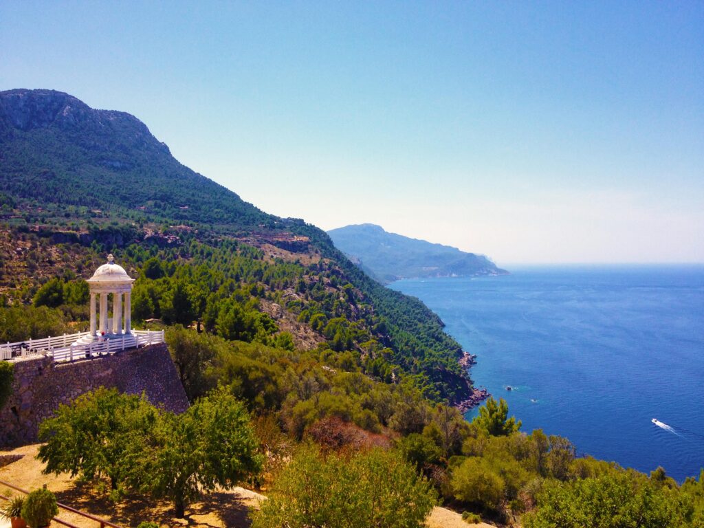 Breathtaking view of Mallorca's coastline featuring a peaceful pergola with lush greenery and azure ocean.