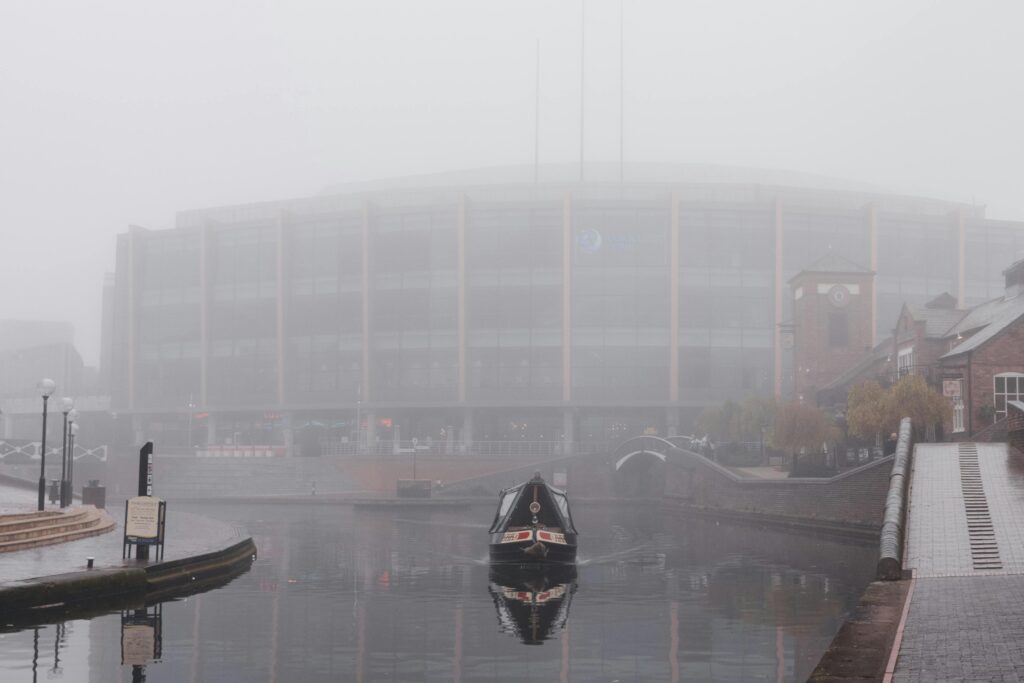 Misty morning on Birmingham canal featuring a narrowboat and modern buildings.