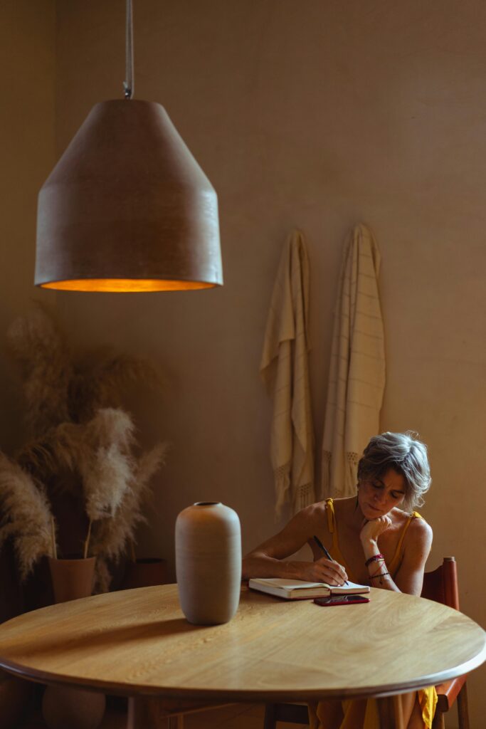 Serene image of a senior woman writing at a table in a warmly lit home environment.