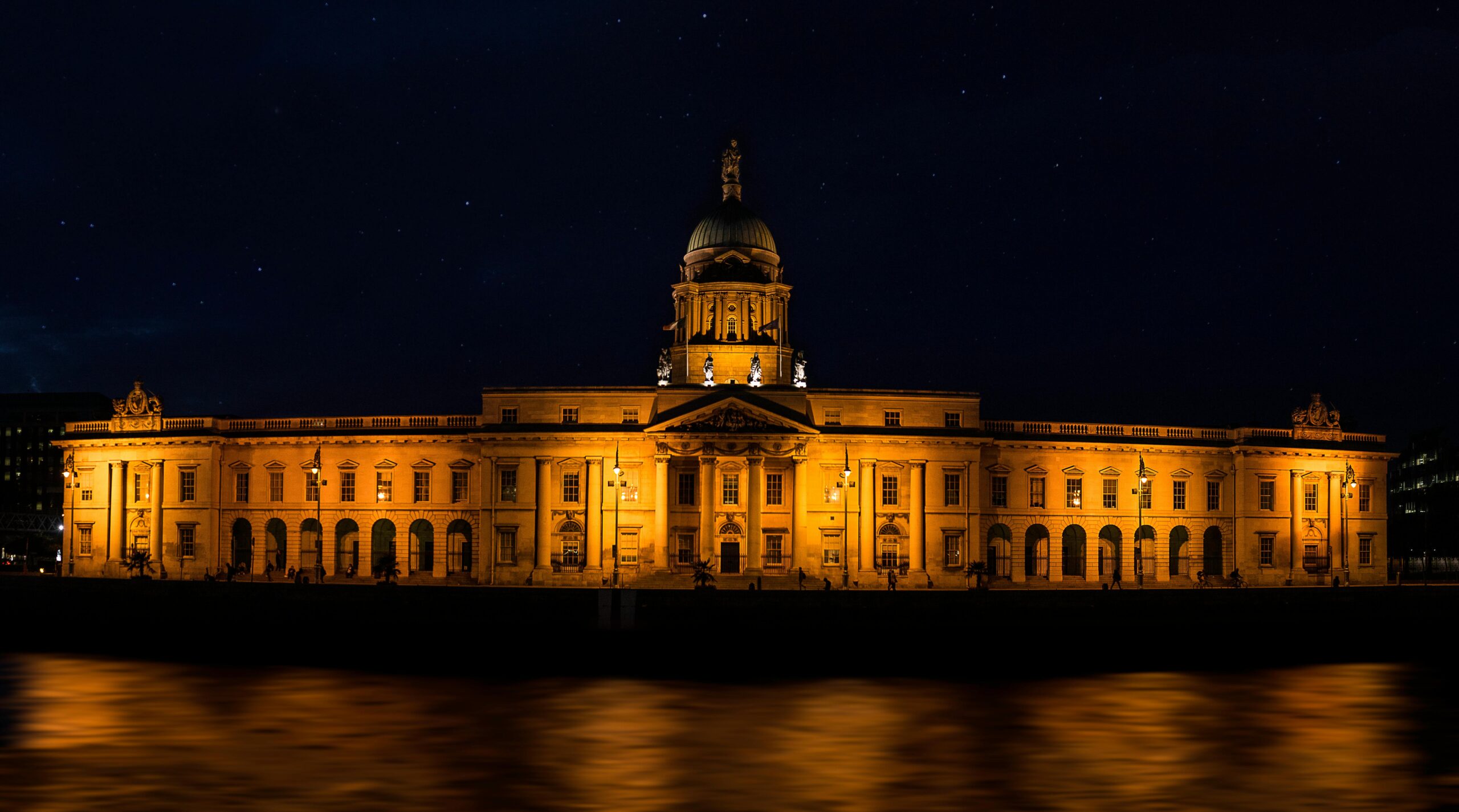 Stunning view of the illuminated Custom House in Dublin by the river at night.
