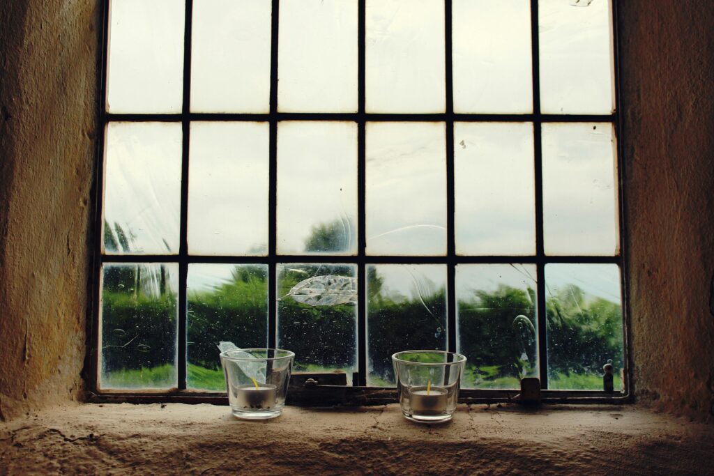 A rustic window with candles overlooking a serene landscape. Ideal for decoration themes.
