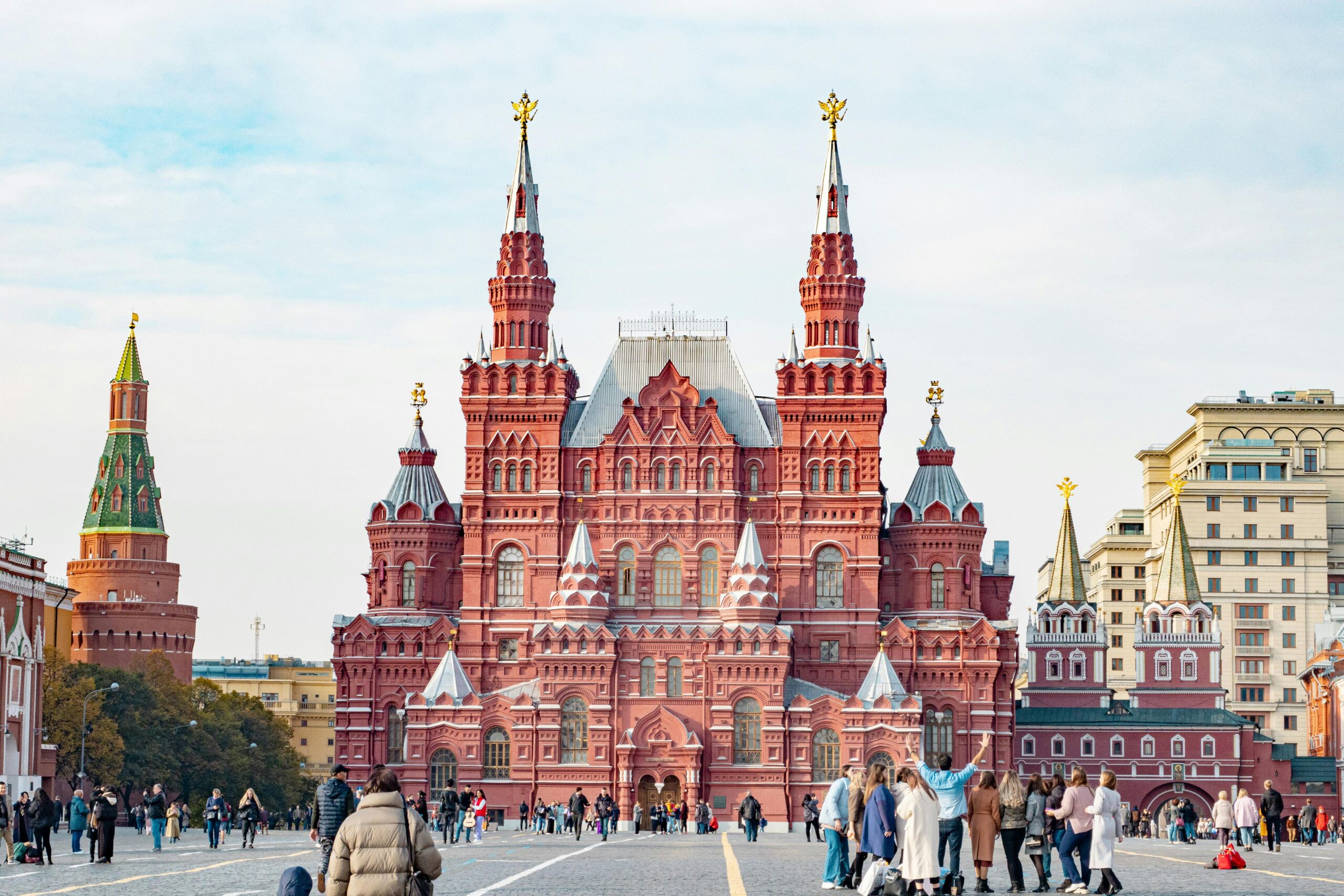 People walking near the historic landmark in Red Square, Moscow cityscape, vibrant urban culture.