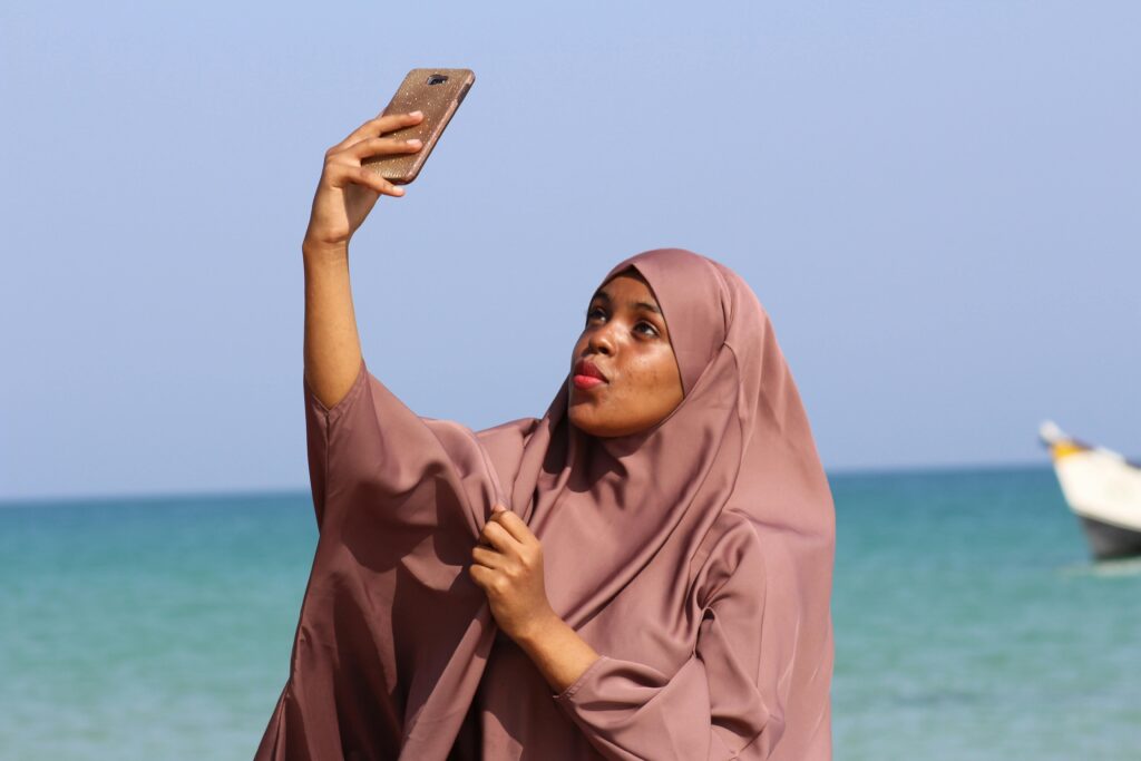 Woman in hijab taking a selfie by the sea in Qandala, Somalia.
