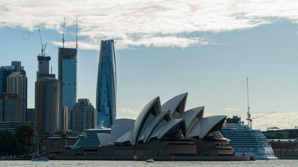 Sydney Opera House with skyline backdrop, featuring iconic architecture and modern cityscape.
