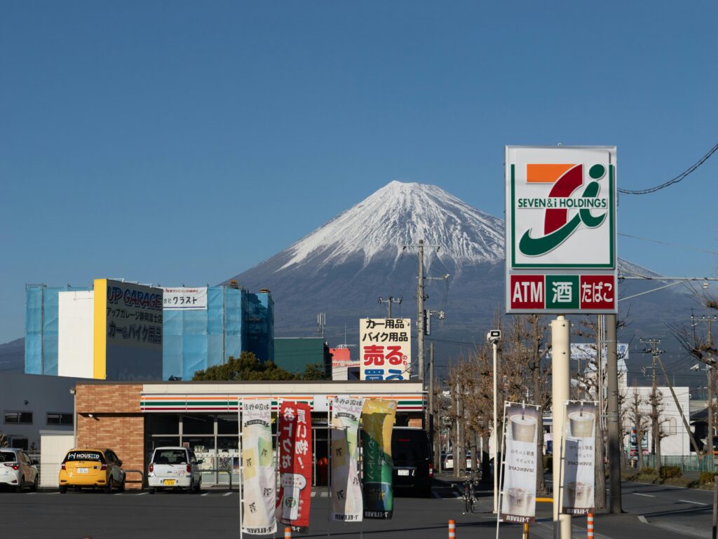 Mount Fuji visible behind a 7-Eleven store sign in Shizuoka, Japan.