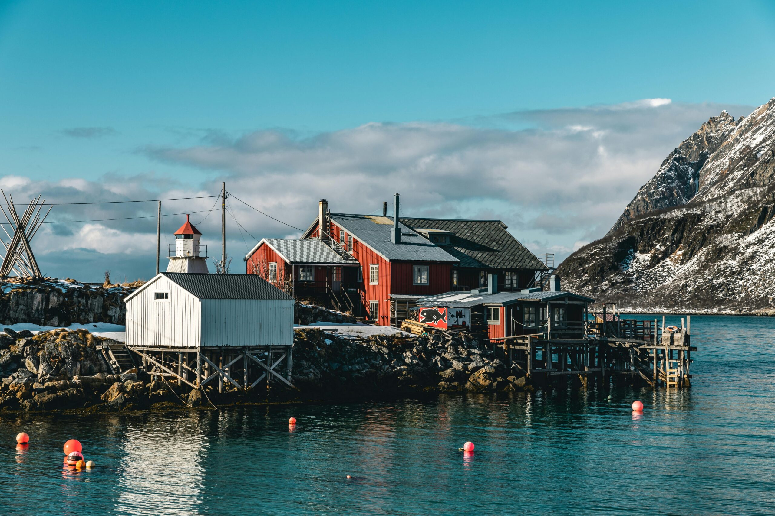 A serene coastal village with a lighthouse, colorful houses, and mountain backdrop, perfect for travel enthusiasts.