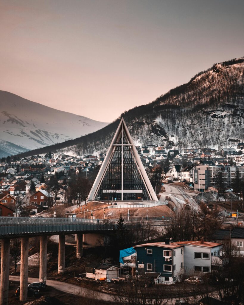 A stunning view of the Arctic Cathedral and snowy mountains in Tromsø, Norway during winter.