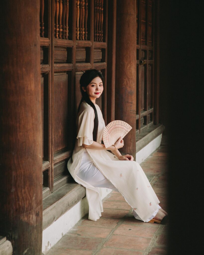 Portrait of a woman in ao dai sitting at Văn Miếu, Hanoi, showcasing Vietnamese culture.