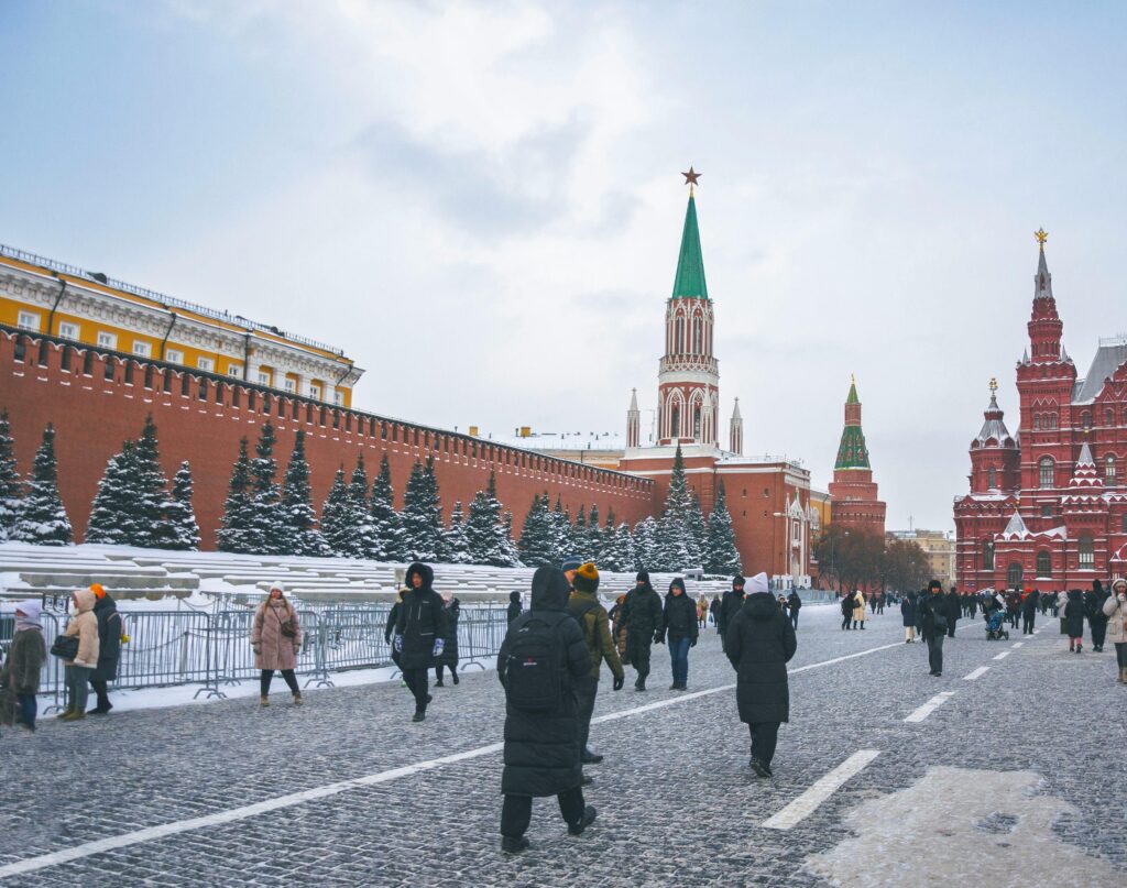 Snow-covered Red Square with St. Basil's Cathedral and people in winter gear.