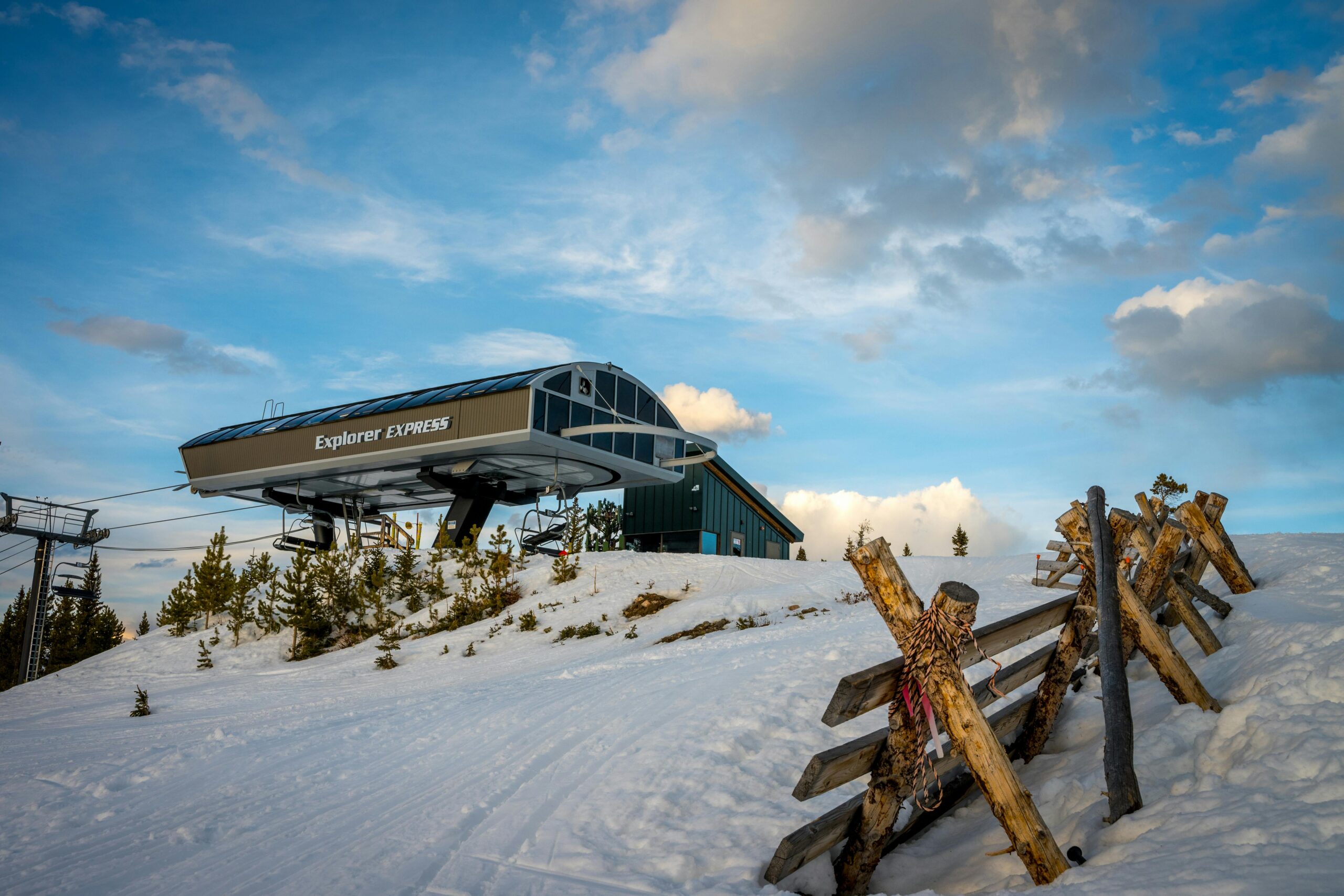 A ski lift named 'Explorer Express' on a snowy mountain under a blue sky with clouds.