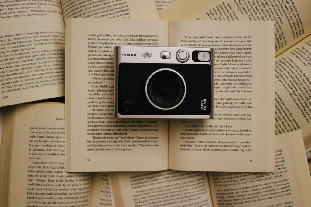 Vintage camera rests on open pages of books, creating an artistic flat lay.
