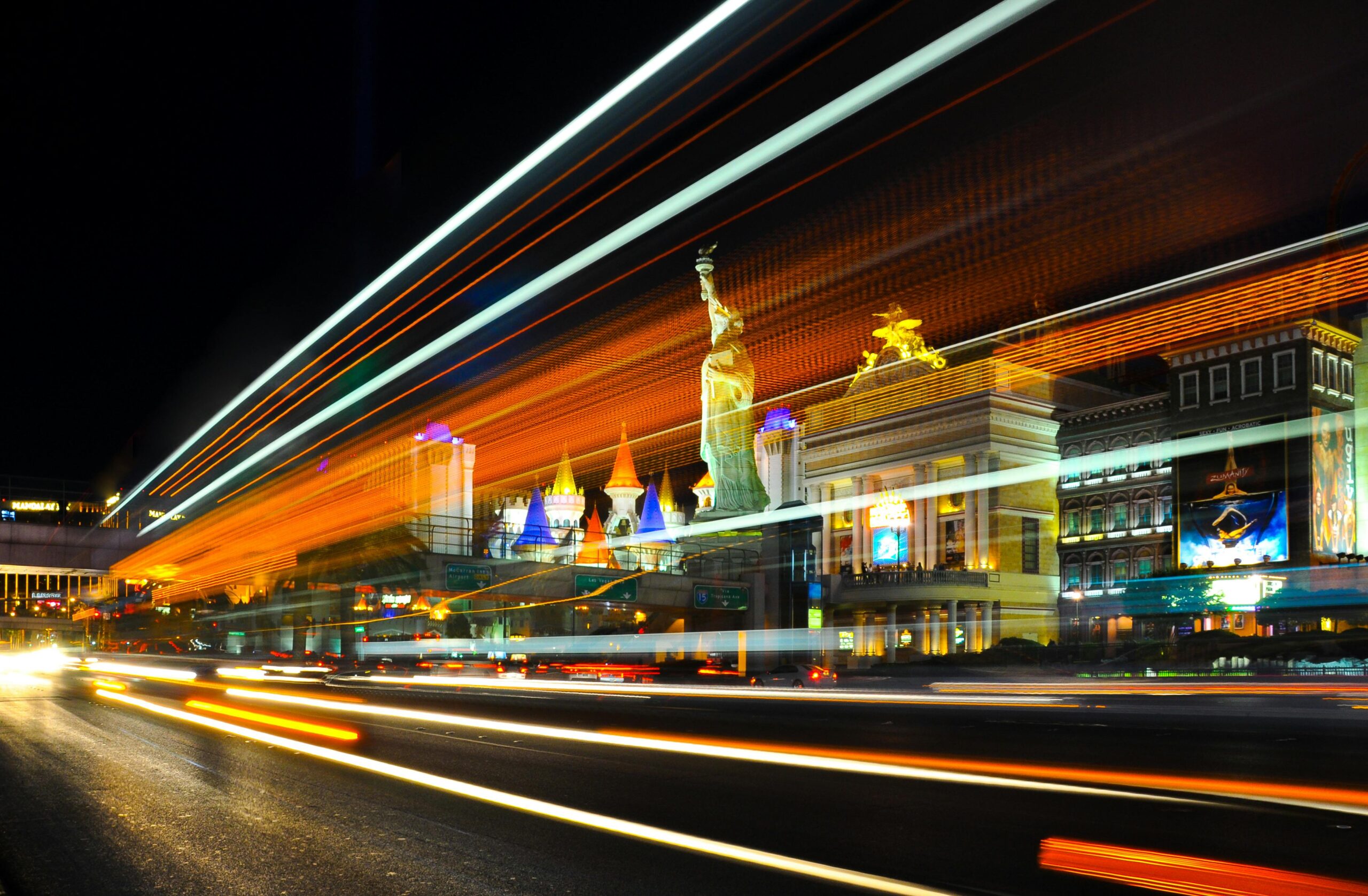 Colorful light trails and iconic landmarks on the Las Vegas Strip at night.