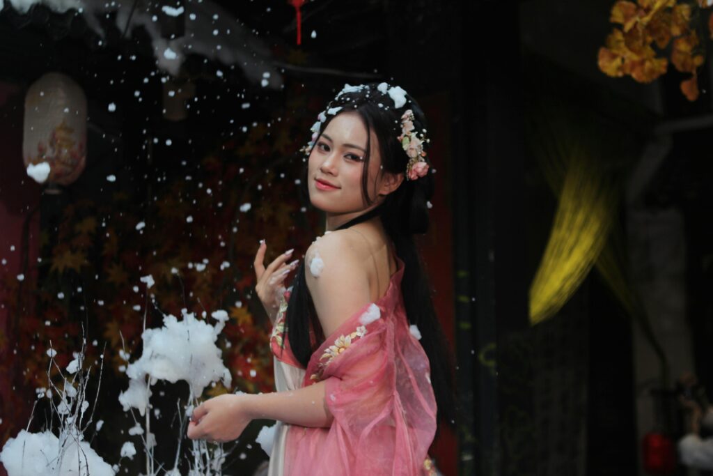 Graceful woman in traditional clothes posing with soft snowfall ambience.