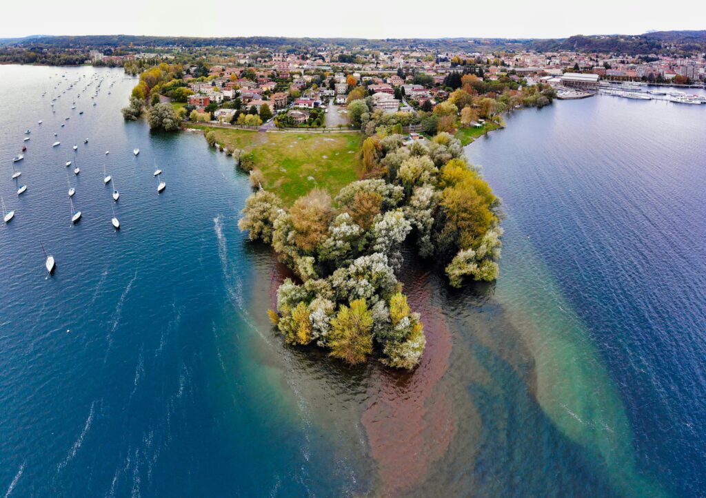 Aerial view of Angera, Italy showcasing a beautiful landscape with clear water and sailing boats.