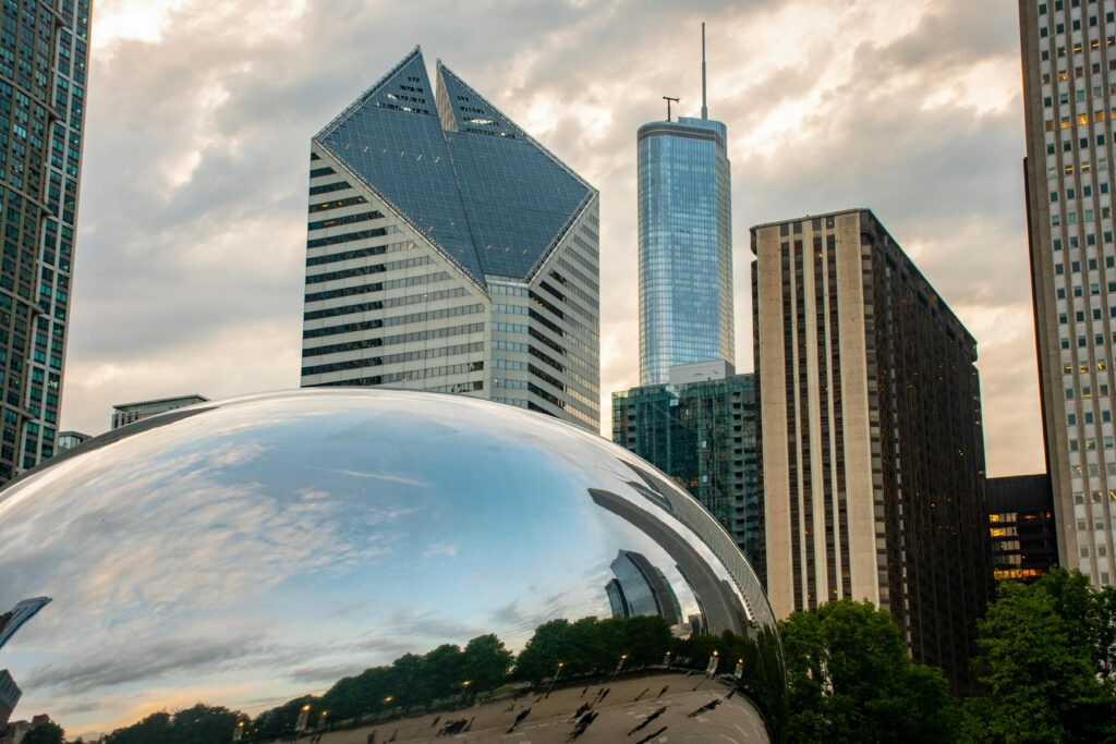 Chicago skyline featuring Cloud Gate sculpture reflecting the sky at sunset.