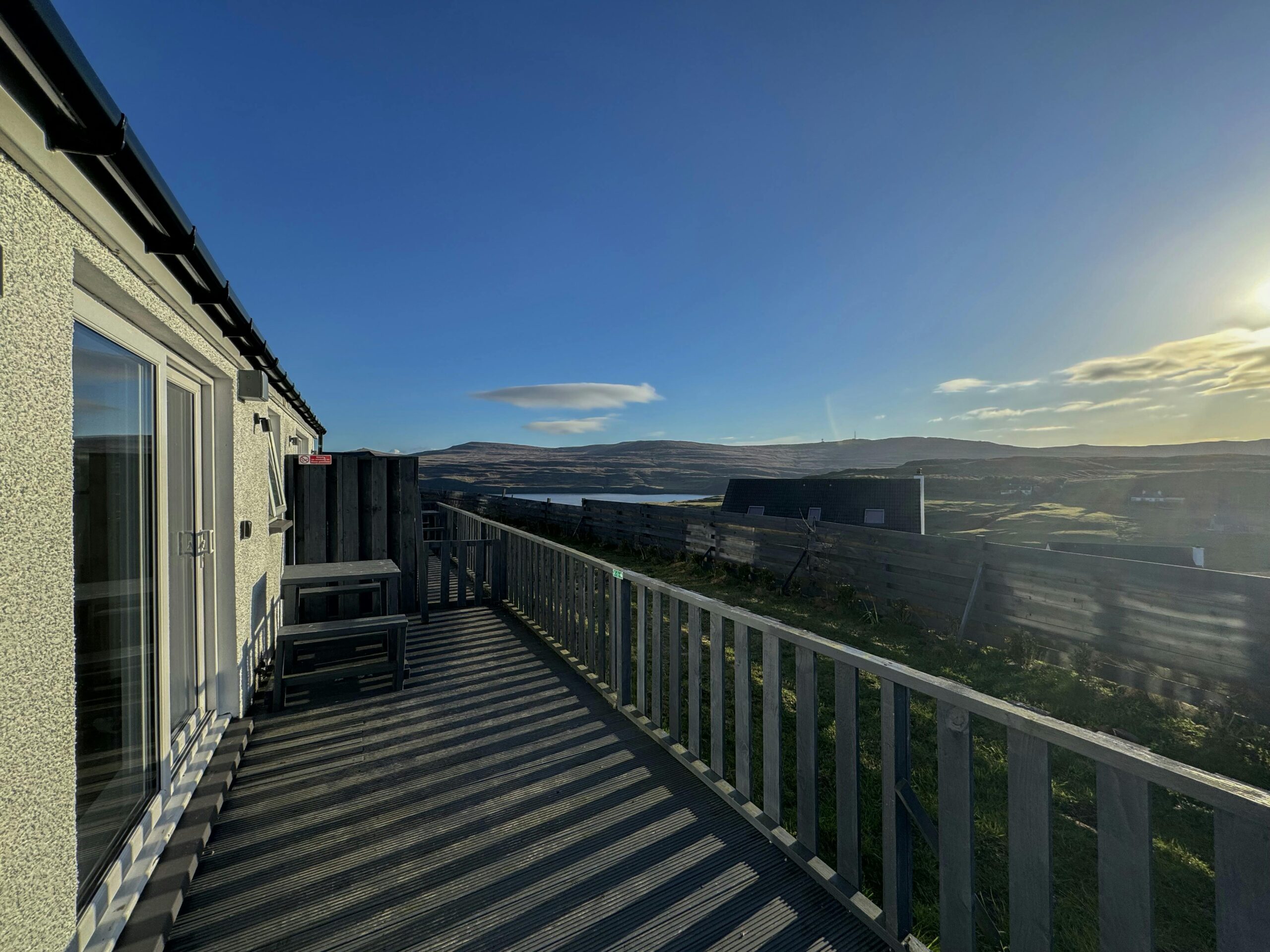 Scenic view of a balcony overlooking the Isle of Skye's rolling hills under a bright, clear sky.