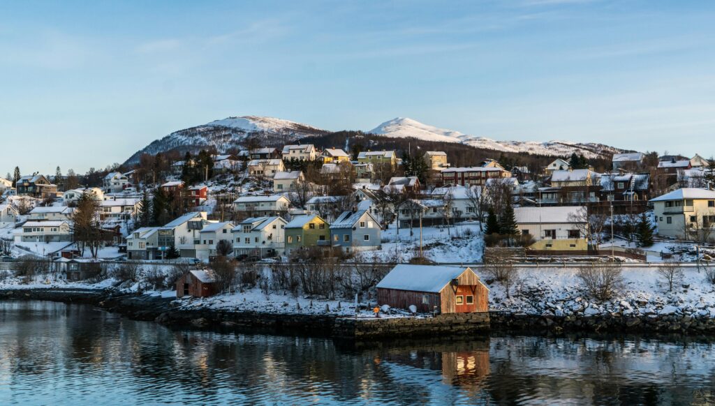 A picturesque Norwegian village with snow-covered houses and a waterfront view, showcasing winter scenery.