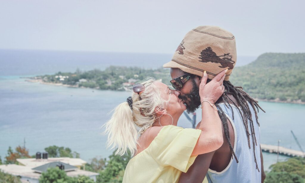 A multiracial couple shares a romantic kiss overlooking the ocean in Jamaica.
