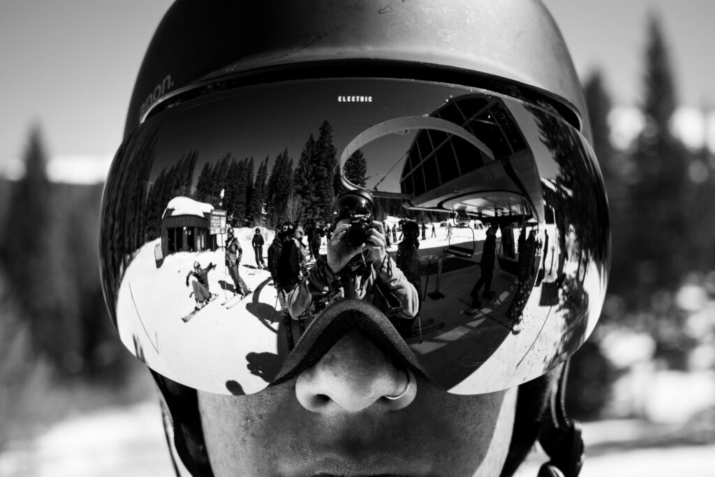 Close-up view of ski goggles reflecting scenic winter landscape and photographer at Winter Park.