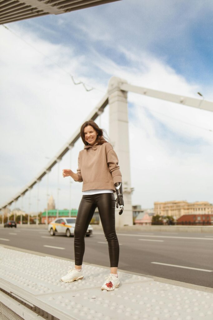 A vibrant portrait of a woman with a prosthetic arm standing confidently on a Moscow bridge.