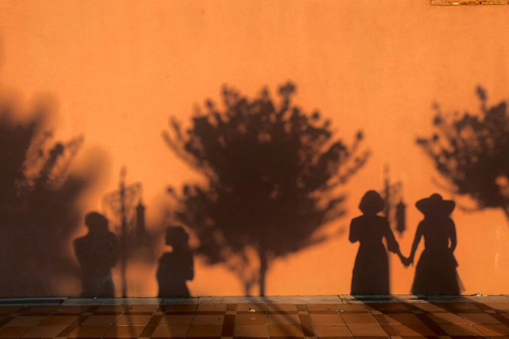 Shadows of people and trees on a sunlit wall create a striking scene in İstanbul.