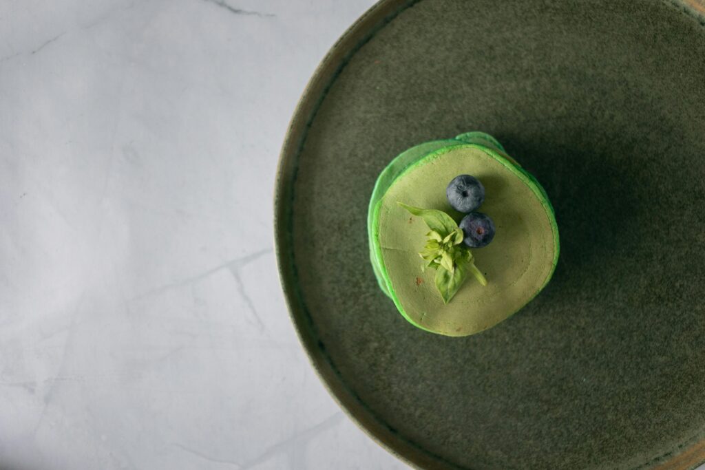 A delicious green matcha pancake with blueberries on a stone plate, perfect for a healthy breakfast.