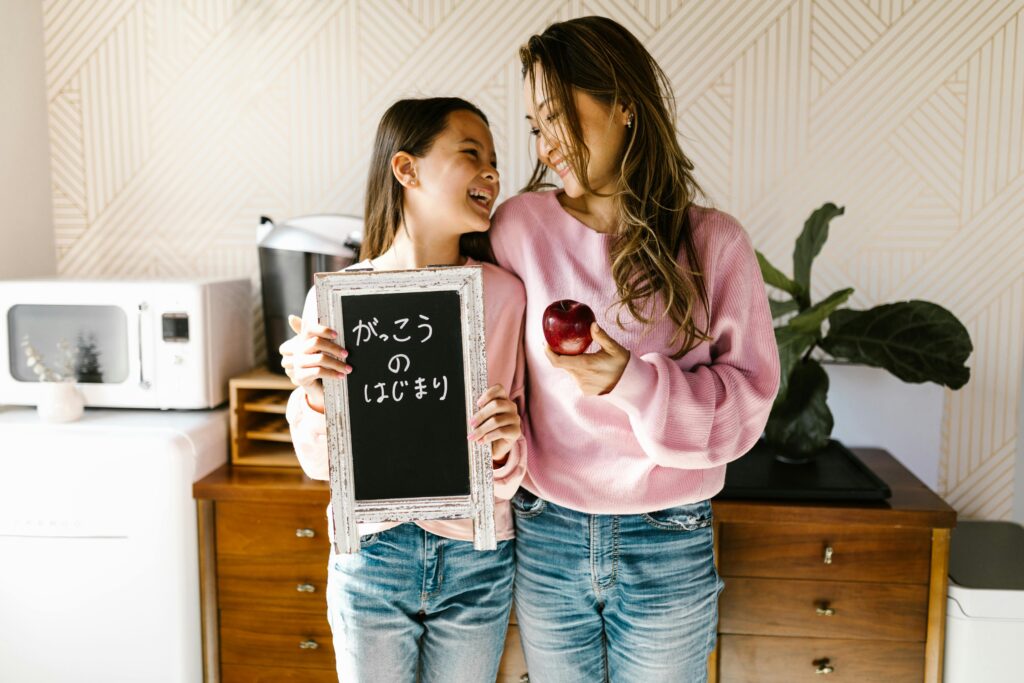 Mother and daughter smiling with a back-to-school chalkboard, creating a joyful family moment.