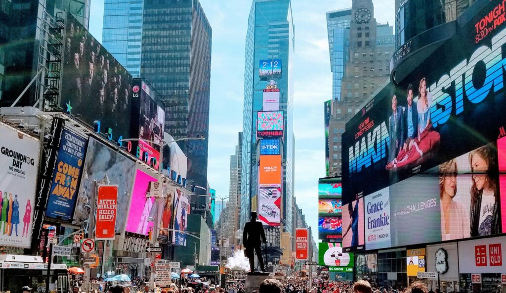Vibrant daytime view of Times Square in New York City, showcasing iconic billboards and skyscrapers.