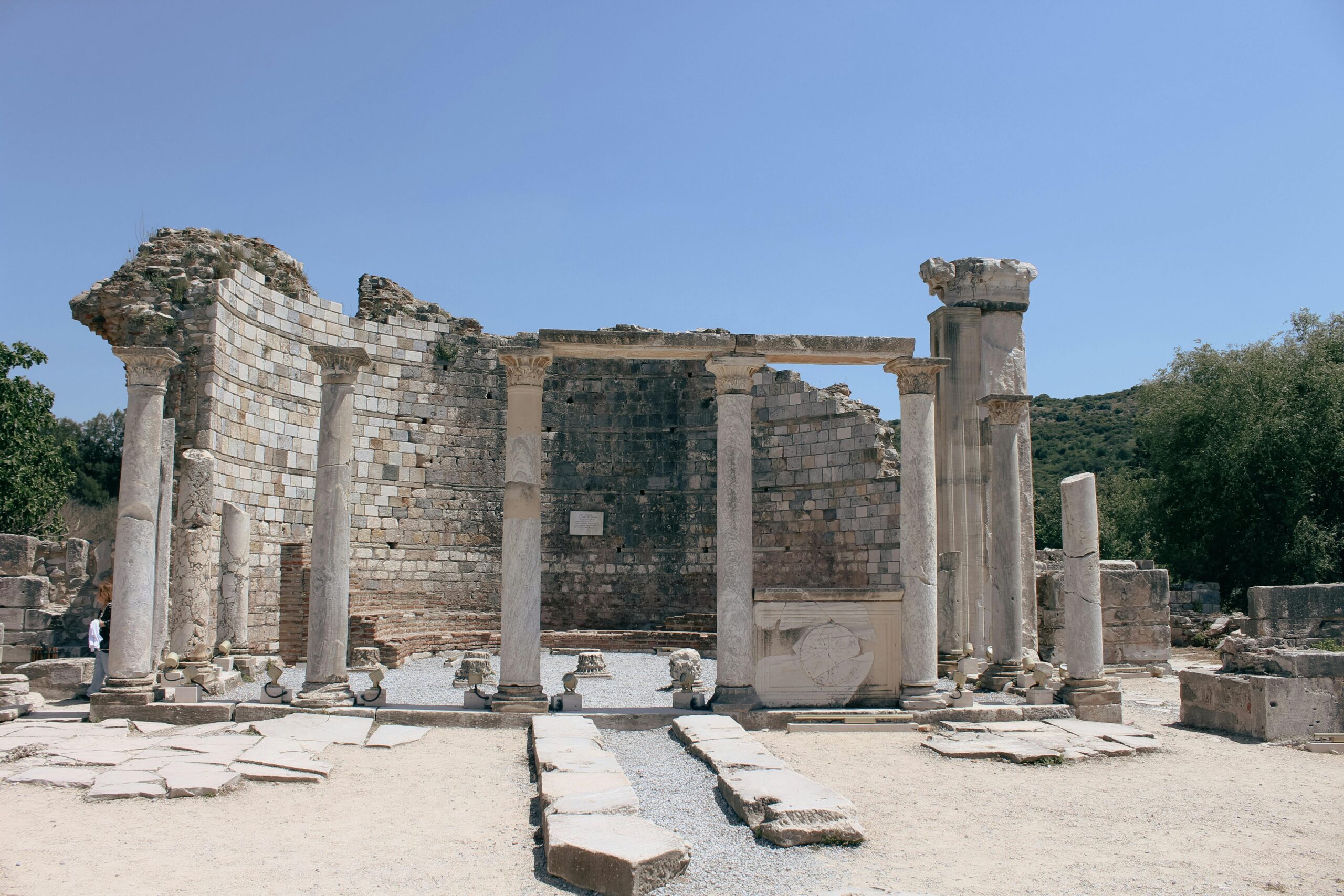 Ancient ruins with stone columns standing tall under a clear blue sky, showcasing historical architecture.