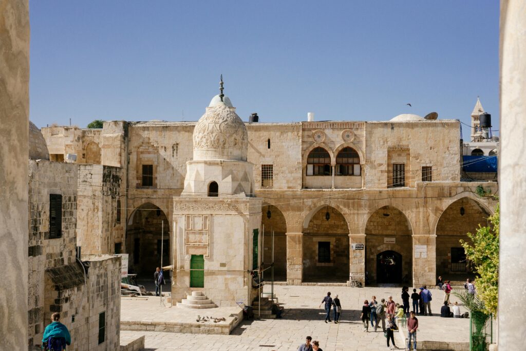 Stone buildings and arches in the Old City of Jerusalem with people exploring the historic site.